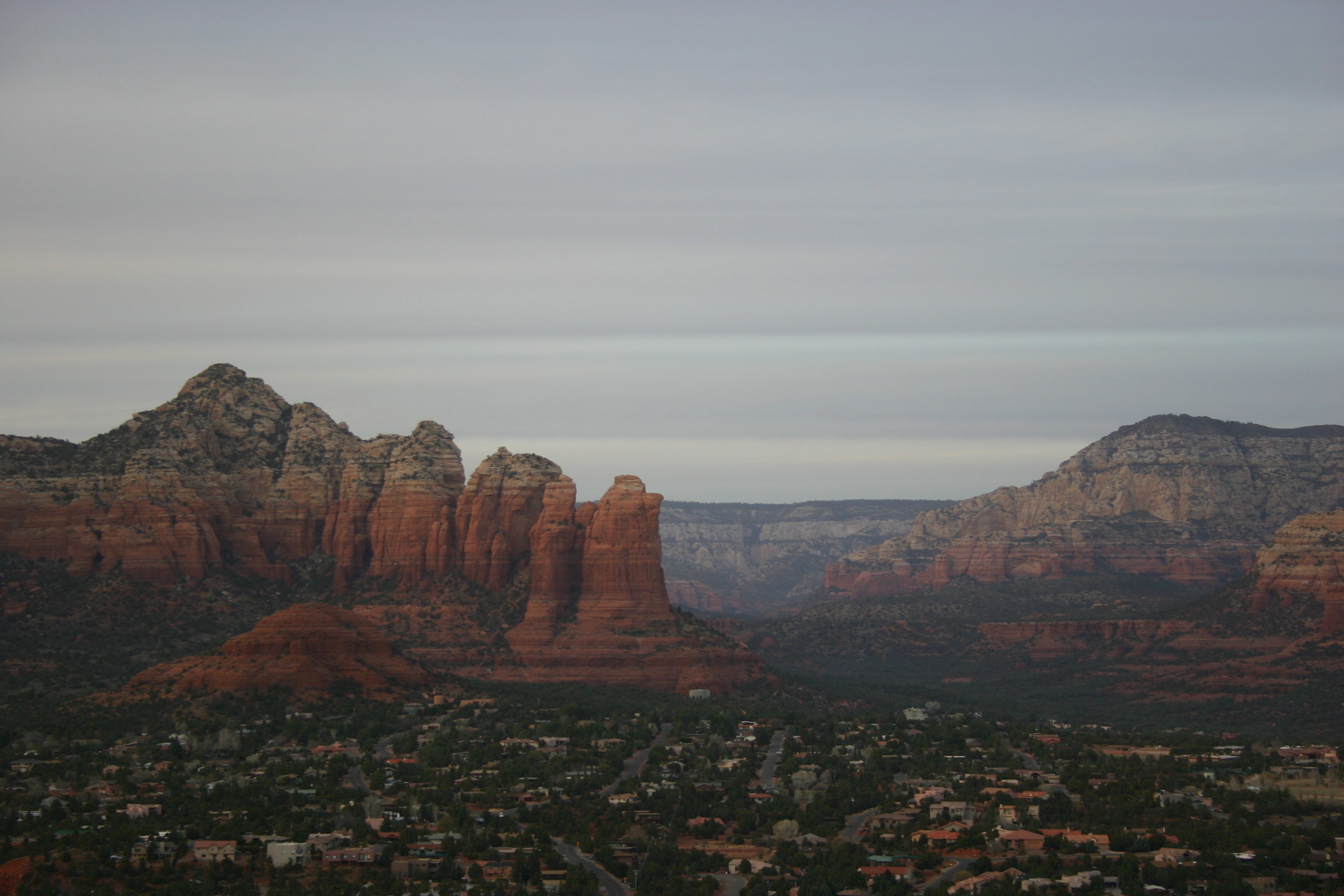 Red rock mountains tower over the city of Sedona at twilight. 