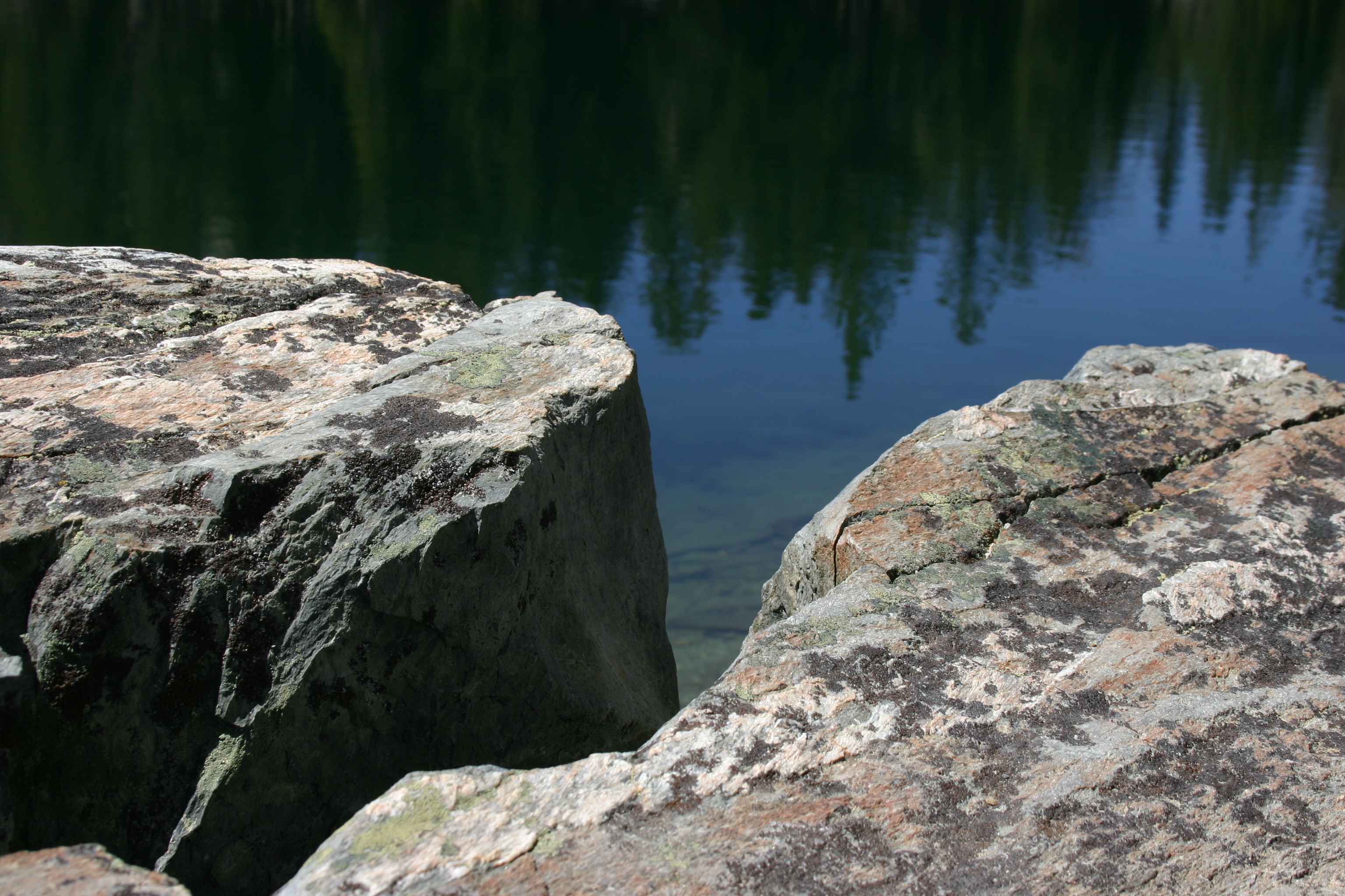 Broken rocks colored with lichen near a lake. 