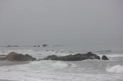 Waves near the rocky coast before a foggy blurred horizon. 