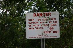 Danger sign near Wailua Falls. Locals use it for target practice. It reads: “Danger. Stop - Do not enter! Slippery rocks at top of falls. People have been killed. Keep out. State of Hawaii Department of Land & Natural Resources.” 