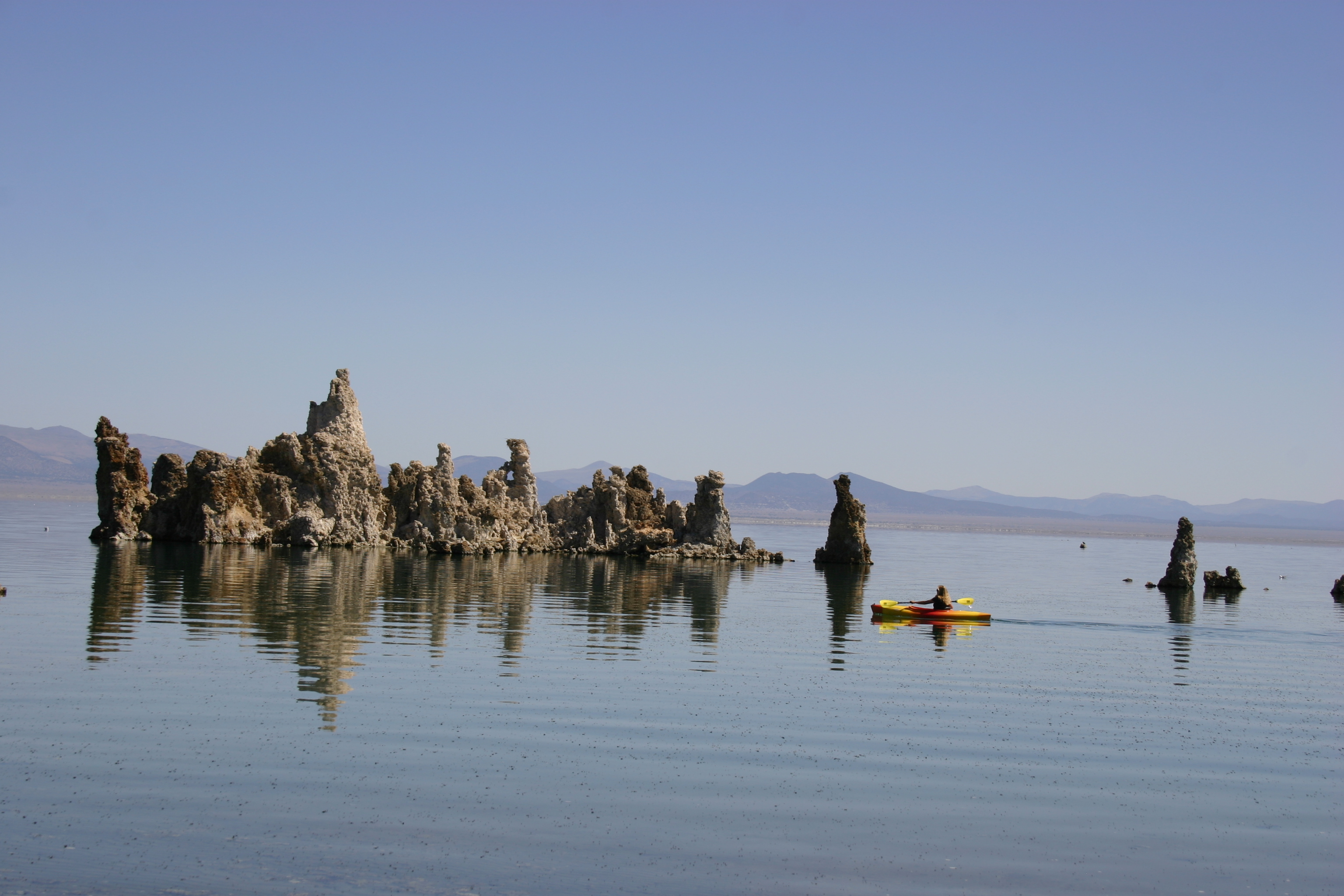 A brightly colored kayaker paddles by tufa towers in Mono Lake. 