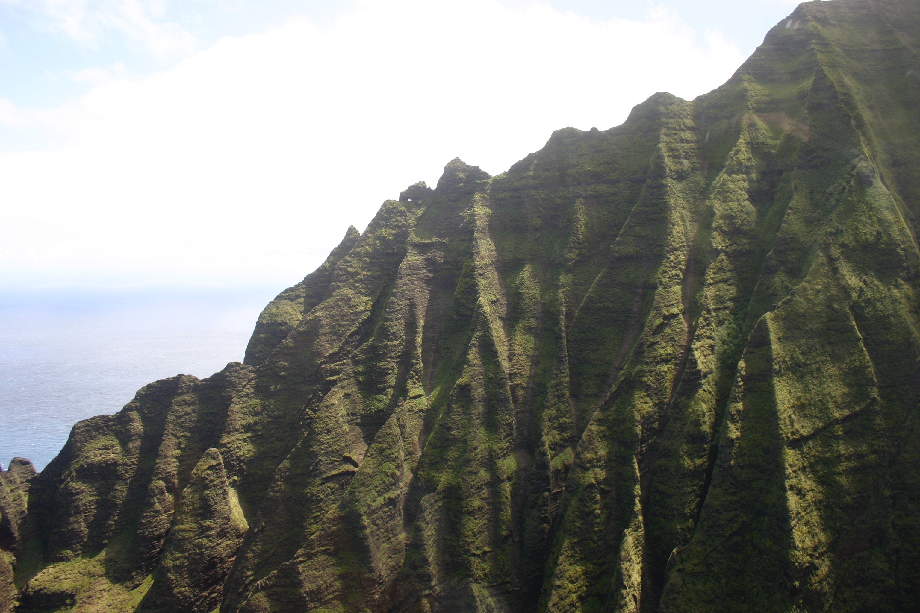 The rugged green cliffs of the Nā Pali coast, seen from a helicopter. 