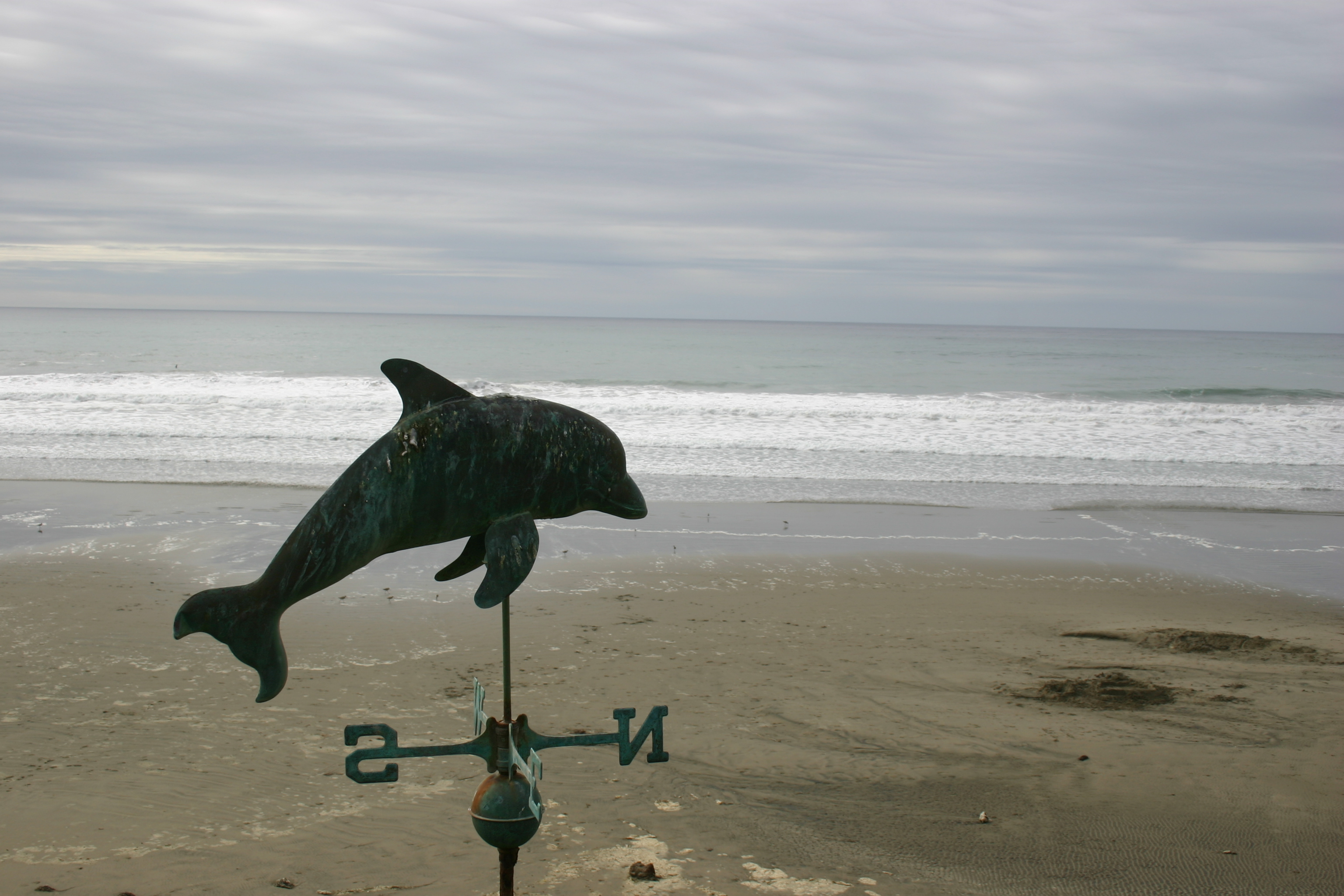Dolphin weathervane on a lonely beach.