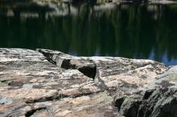 Broken rocks colored with lichen near a lake.