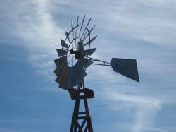 Water-pumping windmill against a cloudy blue sky.