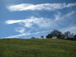 White clouds in a brilliant blue sky over a hill in Pacheco State Park, California.